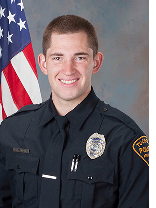Department photo of TPD officer in uniform in front of an American flag.