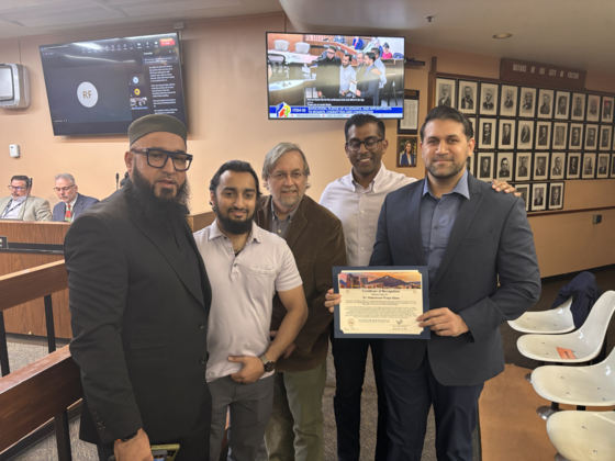 Photo of Imam Syed Hassan Ali, and friends along with Council Member Kevin Dahl next to Dr. Kahn during the presentation.