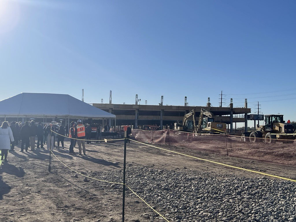 Photo of Groundbreaking ceremony with the construction of the parking garage underway in the background. 