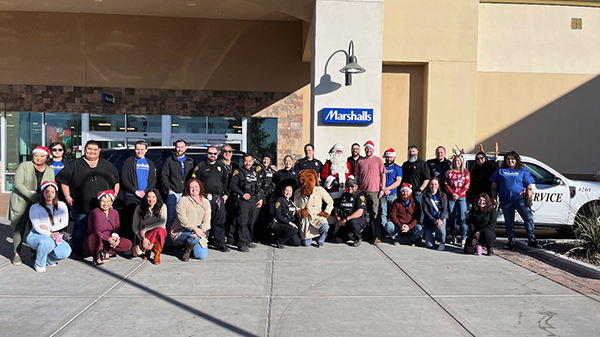 Group photo of TPD members in uniform, Santa, and McGruff, in front of Marshall's.