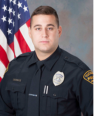 Department photo of TPD officer in uniform in front of an American flag.