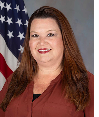 Department photo of female professional staff in front of an American flag.