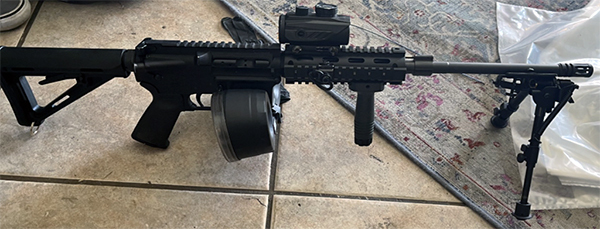 Photo of a rifle on the floor with a drum magazine.