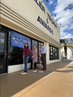 Diana Amado and two representatives from Tuller Trophy made ceremonial marks by holding paint rollers in front of Tuller Trophy building