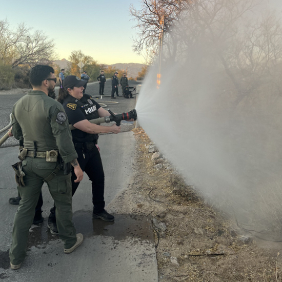 TPD officer in uniform operates a fire hose.