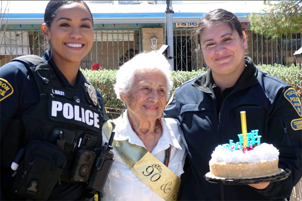 A group photo of 3 women: a TPD officer, the 90-year-old birthday girl, and a TPD CSO holding a birthday cake.