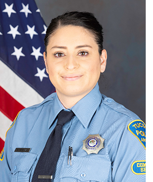 Department photo of a female CSO in uniform in front of an American flag.