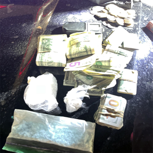 Rolls of cash and a baggie apparently containing drugs laid out on a table.