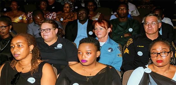 Rows of people in a dark theater. Most are community members. One TPD officer and one CSO are seen in the audience.