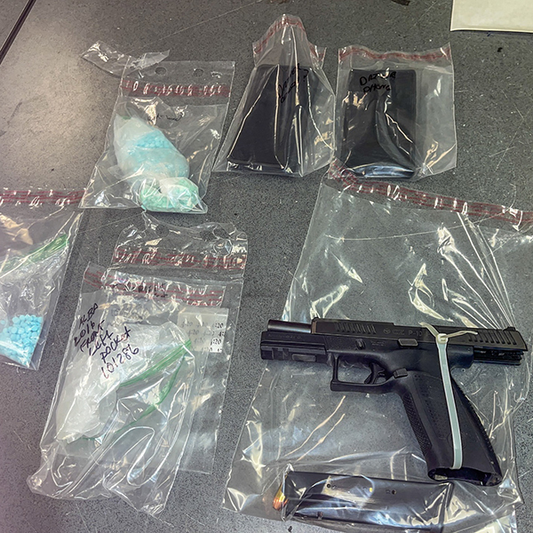 Handgun and drugs in baggies, including blue pills.