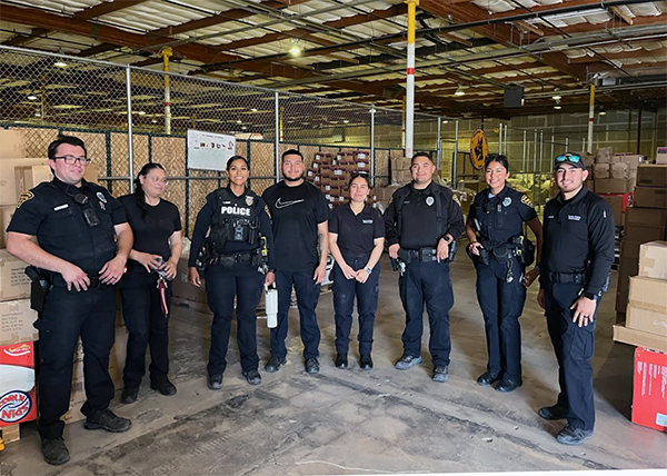 Group shot of uniformed officers in a large warehouse.