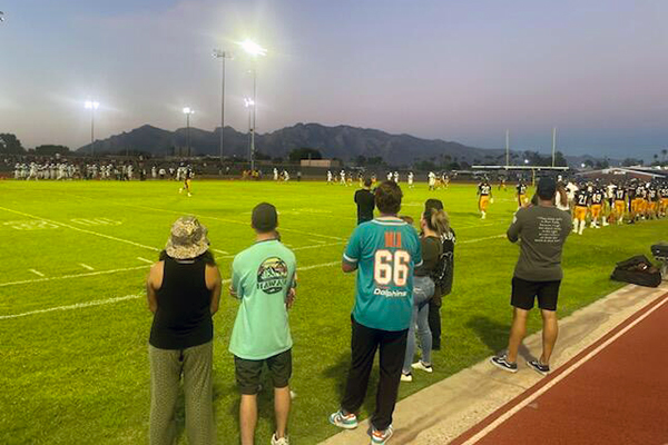 Football field at dusk, with spectators and players.
