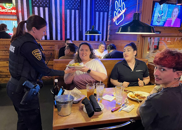 Female TPD officer in uniform serving a table of three at Texas Roadhouse.