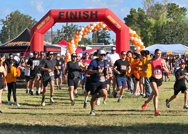 Runners outside racing in front of an inflatable finish line.