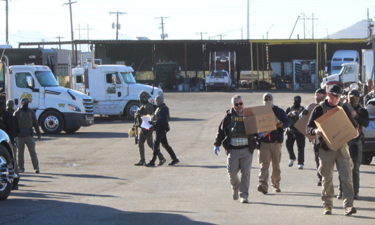 Photo of heavily armed Federal agents carrying boxes out of Noemi trucking.