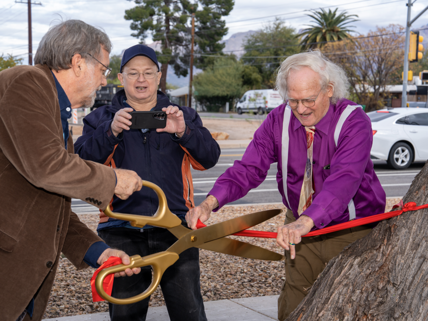 Photo of Council Member Dahl and Dr. Spark cutting parts of the ribbon to take as mementos.