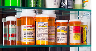 Medicine cabinet showing many bottles of prescription pain pills.