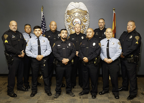 Group photo of officers and CSOs in uniform, surrounded by an American flag and an Arizona flag. Several are older.
