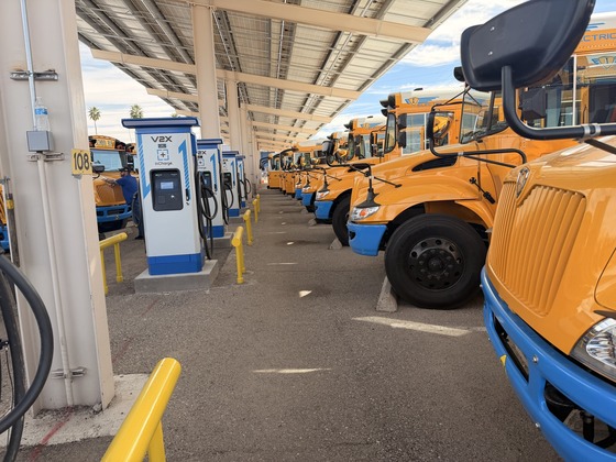 Photo of Electric buses parked alongside their chargers ready to transport students. 
