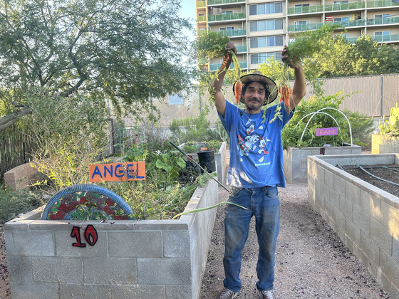 photo of Long-time Blue Moon gardener, Angel, proudly holding crops he harvested from his plot. 
