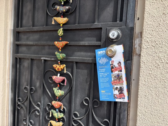 Image of Cyclovia Flier hanging on a knob of a wrought iron door.