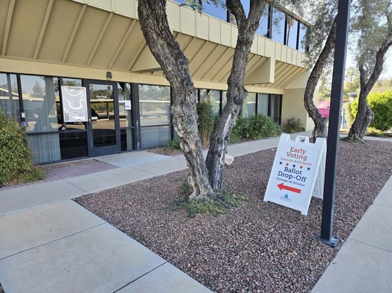 A photo of the Ward 2 early voting center. A sign sign sits on the sidewalk welcoming people to come in.