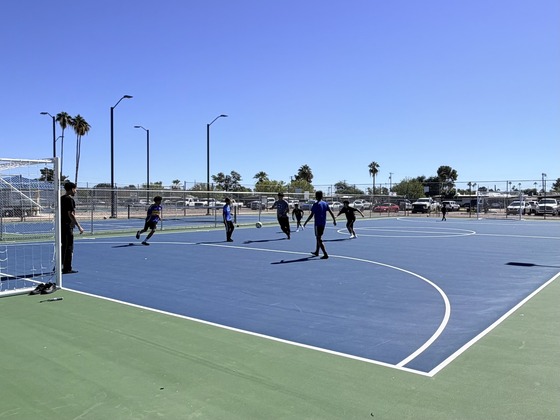 about 10 kids playing with a ball on a futsal court at Jacobs Park