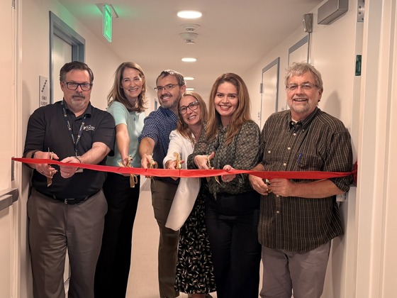 City staff cut a red ribbon in a Tucson House Hallway