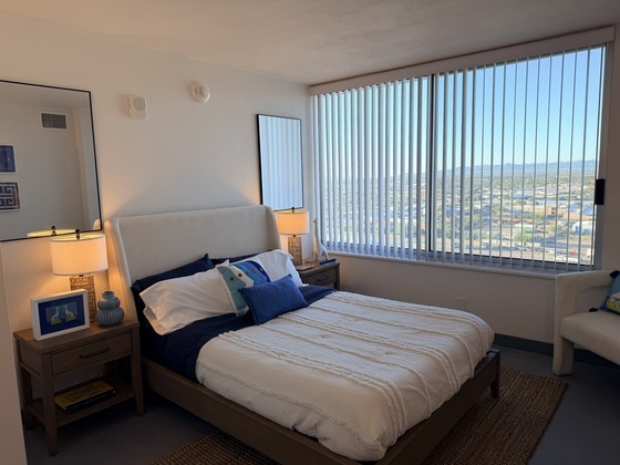 a bed with the sheets drawn up, bedside tables and lamps, and a large window view 