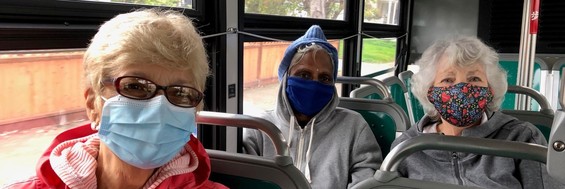Three older adult people sit on a bus