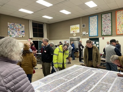 A crowd of people looking at maps on tables