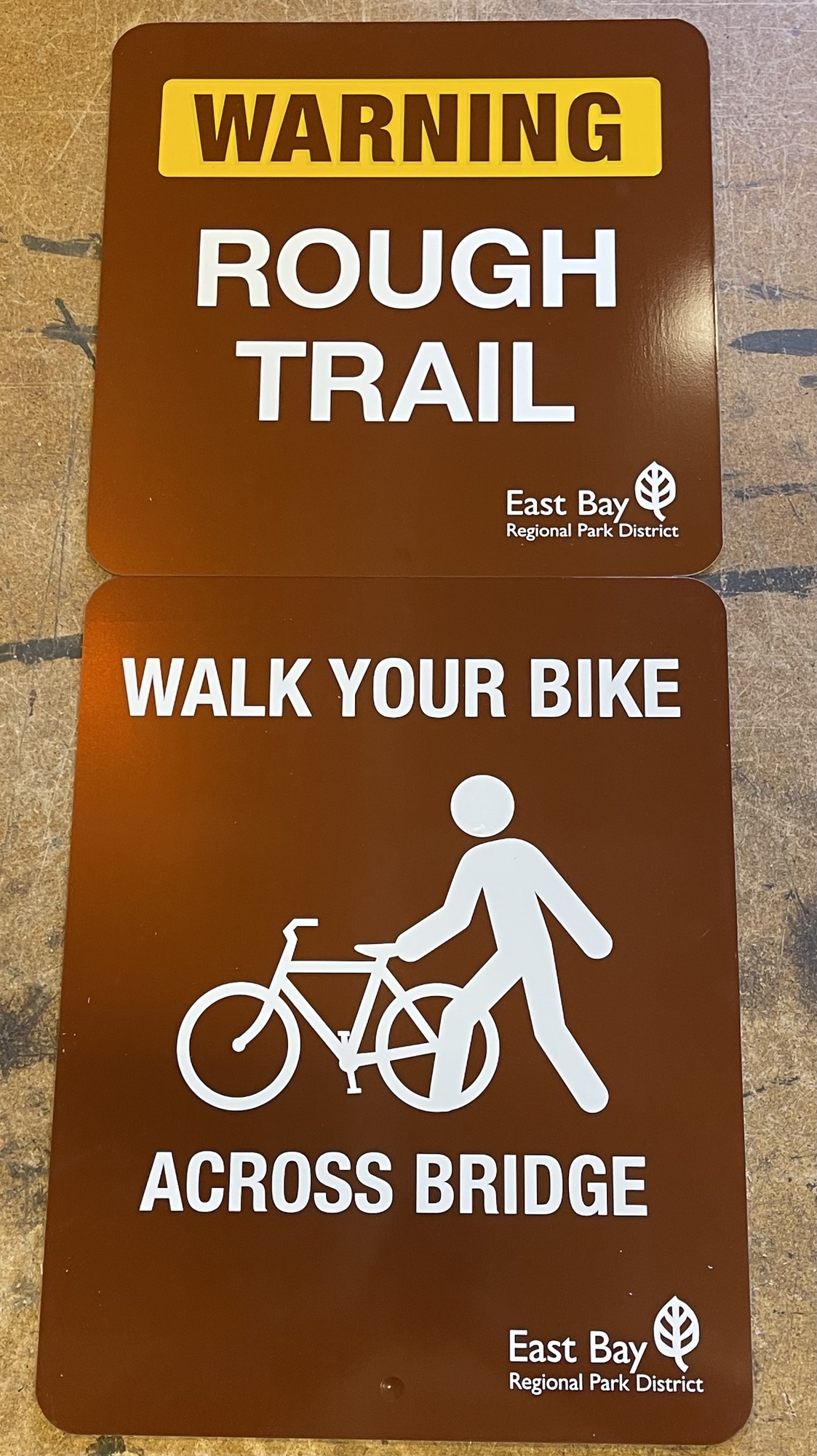 Photo of sign that says Warning Rough Trail - Walk Your Bike Across Bridge