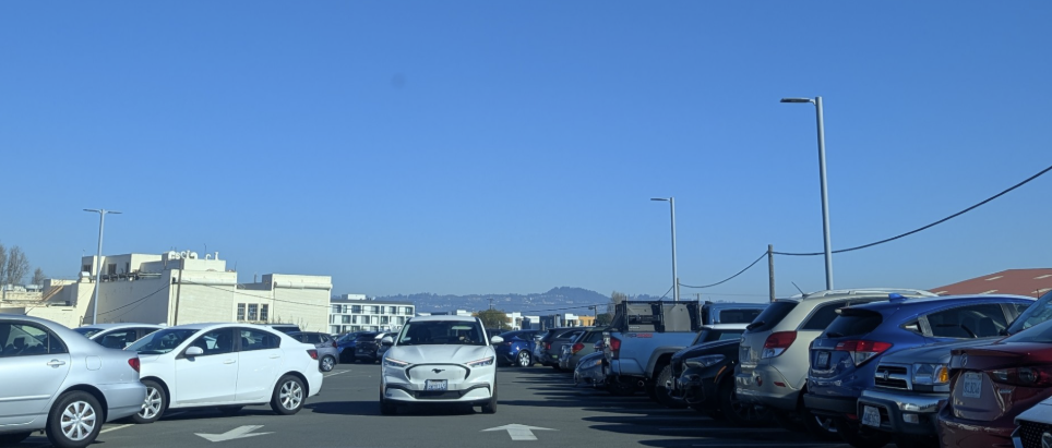 A parking lot completely full, with some illegal parking and another vehicle driving