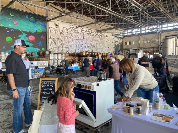 People talking at a booth and looking at an induction stove