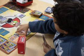 Kids setting down pokemon card in gameboard