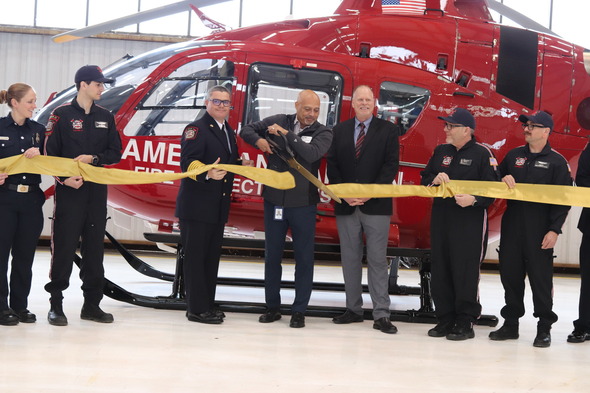 Chair cutting Gold Ribbon in front of 'Copter 11'