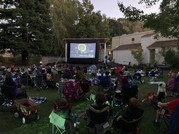People sitting on lawn chairs at dusk watching a big inflatable screen