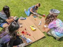 group of middle schoolers doing outdoor craft on grass