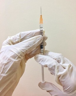 Vaccine Needle held upright by two gloved hands