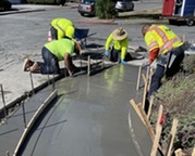 Crews laying cement to install an ADA ramp