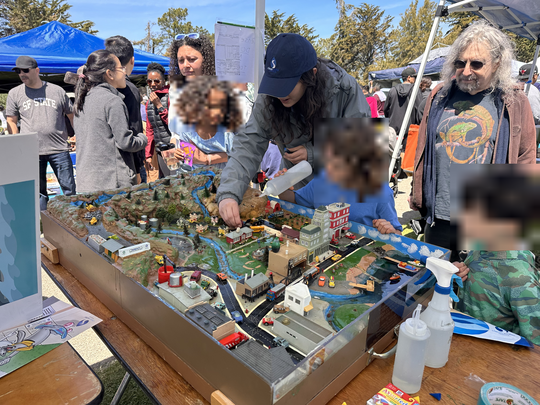 Young environmentalists learn about the storm water system in Berkeley by participating in a diorama demonstration of Berkeley's runoff patterns.