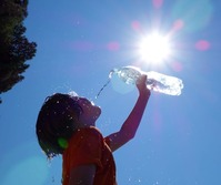 Photo of kid drinking water under hot sun