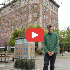 Photo of man standing in front of Culver Hotel with play button for video