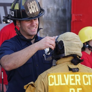 Photo of CCFD Girls Camp with firefighter helping child with mask