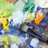 Paint brush on top of colorful dried paint