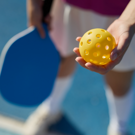 Person holding pickleball and paddle
