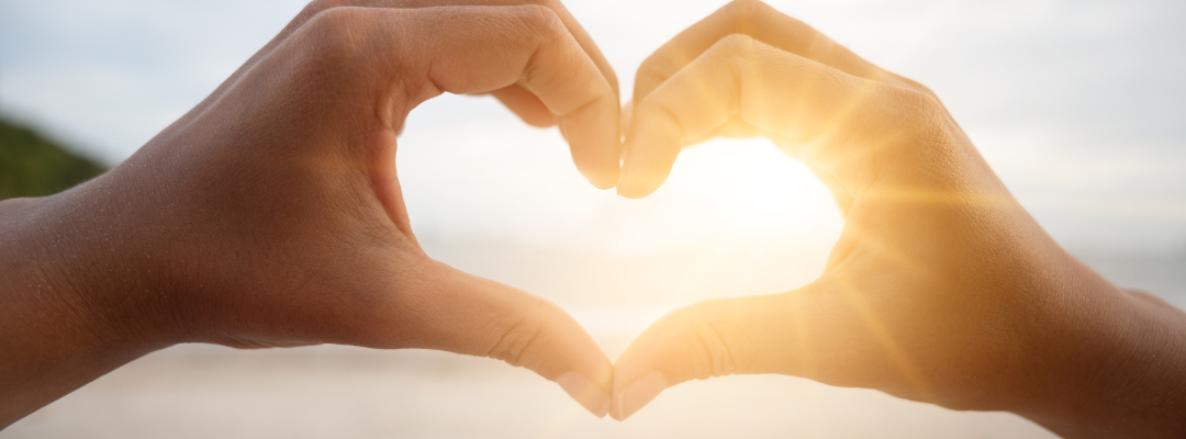 Hands making a heart with sunbeams shining through