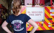 Woman standing in front of Fire Truck with "El Segundo Fired Up Girls Camp" shirt on.