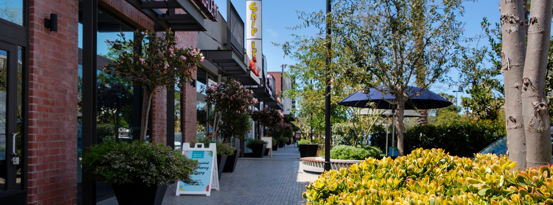 Courtyard of The Works shopping center with trees, shops, and flowers
