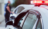 Police car with lights and officer approaching a vehicle